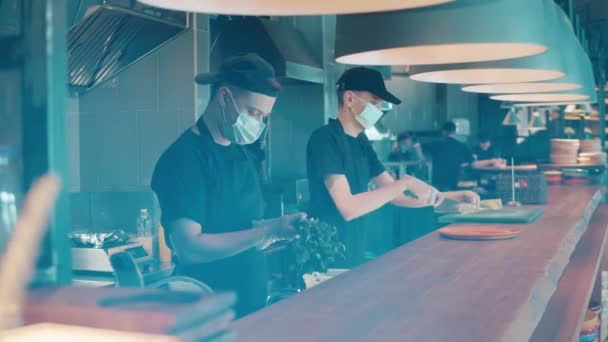 식당 종업원들 이 마스크를 쓰고 음식을 요리하고 있다 — 비디오