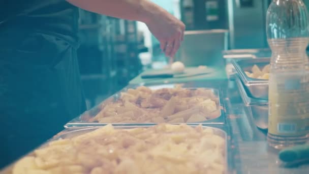 Batatas em bandejas estão ficando temperadas por um cozinheiro — Vídeo de Stock