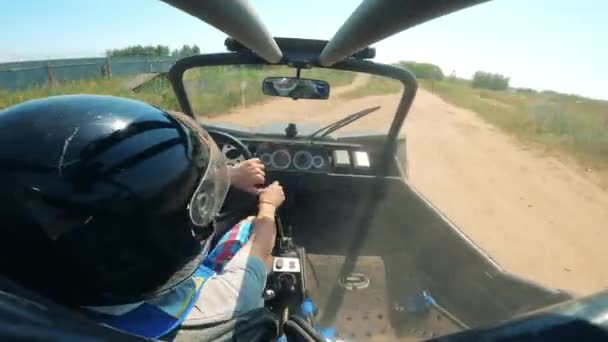 Een persoon rijdt met een raceauto over het terrein — Stockvideo