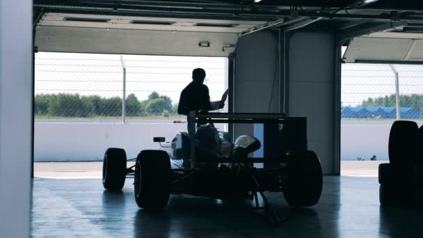 A man with a laptop is inspecting a racing car — Stock Video