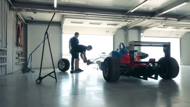 Mannen experts repareren een raceauto in de garage. — Stockvideo