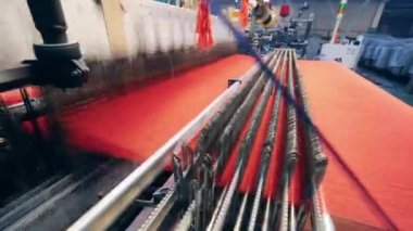 Fabrika mekanizması kırmızı ipliklerden kumaş dokuyor.