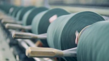 Tekstil makinelerinde iplik makaraları yakın plan çekimde dönüyor