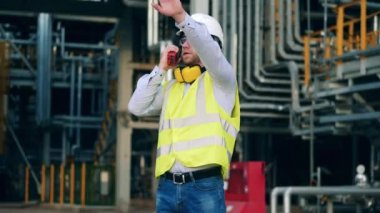Güvenlik görevlisi petrol rafinerisinde telsiz kullanıyor.