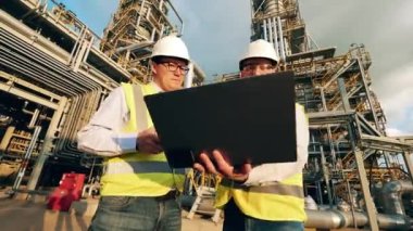 Mühendislik meslektaşları petrol rafinerisinde bir konuşma yapıyorlar.