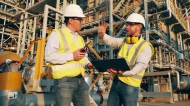 Endüstriyel işçiler petrol rafinerisini tartışıyorlar.