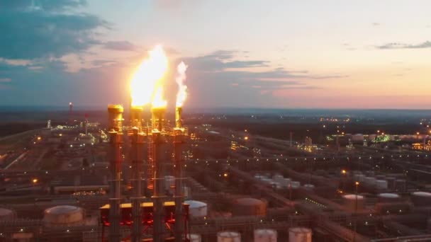 Las pilas de bengalas de la refinería de petróleo están liberando fuego al atardecer — Vídeos de Stock