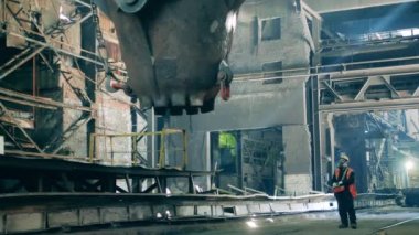 Metalürji uzmanı kepçenin havadan taşınmasını izliyor.