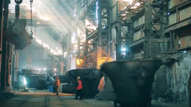 Steel ladle is being relocated by air with plant workers watching it — Stock Video