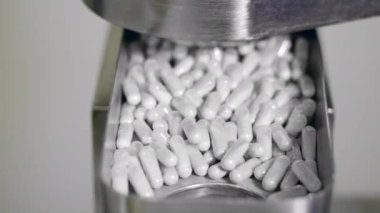 Kapsül hapları metal taşıyıcıdan düşüyor.