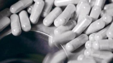 Kapsül hapları yakın planda bir deliğe düşüyor.