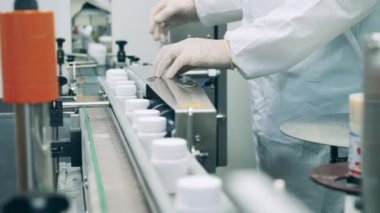 Fabrika işçisi ilaç tüpleriyle bir taşıyıcı düzenliyor.