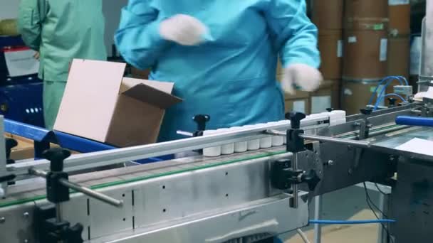 Plant worker is putting pill tubs into a box — Stock Video