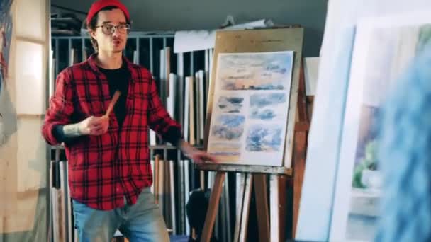 Učitel výtvarného umění vysvětluje obrázky krajiny během lekce — Stock video