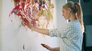 Sarışın kadın çıplak elle soyut bir resim çiziyor.