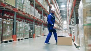 Erkek çalışan bir kutuyu yerleştirirken ergoskeleton kullanıyor