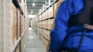 Erkek çalışan depoda bir kutu taşıyor.