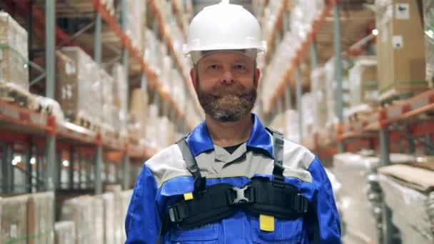 Hombre trabajador de almacenamiento en un hardhat y ropa de trabajo — Vídeos de Stock