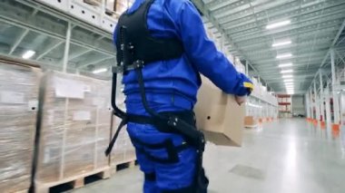 Depo işçisi iş yerinde ergoskeleton giyiyor.