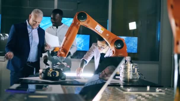 Groupe de scientifiques masculins regardent un bras robotique tout en dessinant — Video