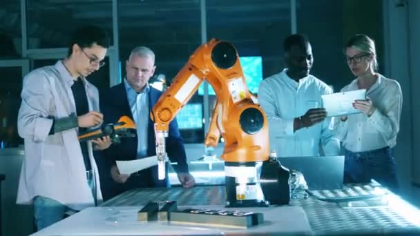 A equipa de investigadores está a realizar uma experiência com um braço robótico. Engenheiros profissionais trabalhando em laboratório industrial moderno. — Vídeo de Stock