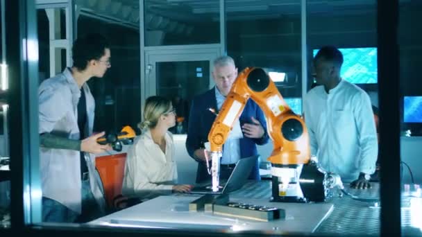 Grupp av forskare pratar medan du tittar på en robot — Stockvideo