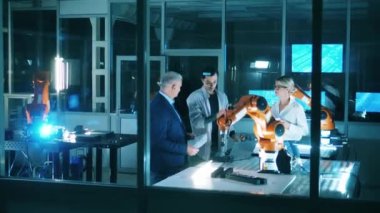 Bilim adamlarından oluşan bir ekip robot kolu tartışıyor. Modern endüstriyel laboratuvarda çalışan profesyonel mühendisler..