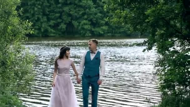 Άνδρας και γυναίκα, νεαρό ευτυχισμένη παντρεμένο ζευγάρι κοντά στη λίμνη. — Αρχείο Βίντεο
