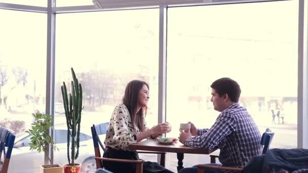 Feliz pareja amorosa en la cafetería riendo, bebiendo té. usando la tableta para la diversión. Primera cita . — Vídeo de stock