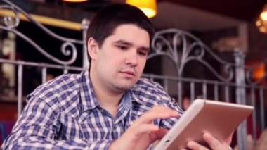 Genç adam kafede tablet bilgisayar dokunmatik ekran kullanma.