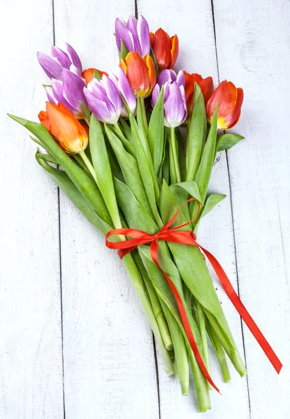 Beau bouquet de tulipes violettes et rouges sur fond bois — Photo