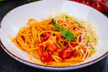 Geleneksel İtalyan makarnası. Beyaz tabakta domates, parmesan peyniri ve fesleğen..