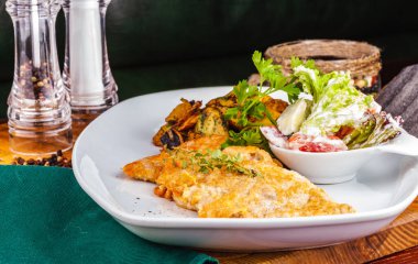 Sebze salatalı tavuk şnitzel ve beyaz tabakta mantarlı kızarmış patates.