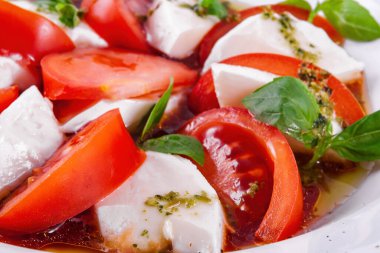 Caprese salad with pesto sauce on a white plate