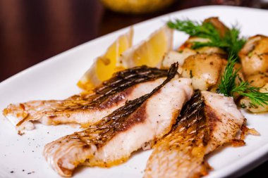 Beyaz tabakta fırında patatesli sazan bifteği