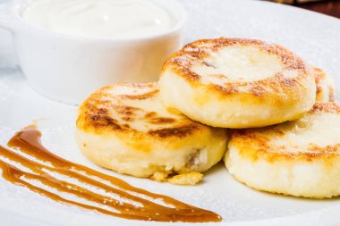 Kahvaltıda. Beyaz tabakta ekşi kremalı süzme peynirli krep.