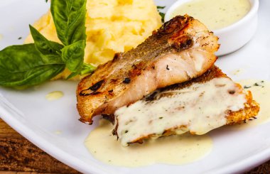 Beyaz tabakta patates püresi ve kızarmış balık.