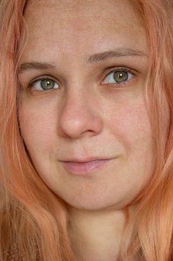 Makyajsız turuncu saçlı ve cildine dokunan kızın yakın plan portresi..