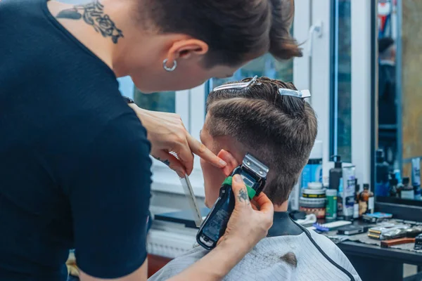 Беларусь - 14 октября 2020 года: Татуированная женщина-парикмахер стрижет парней — стоковое фото
