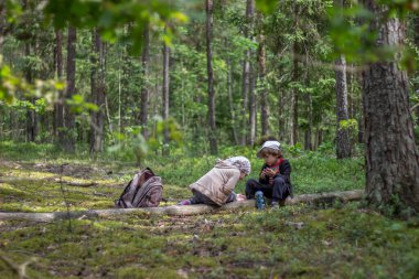 Erkek ve kız kardeş ormanda yürürken dinleniyorlar.
