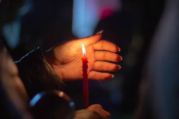 Eine Frau hält eine Kerze in der Hand, die die Flamme des Windes mit ihrer Handfläche bedeckt, zum Gedenken an die Toten, Getöteten, Toten, Verstorbenen, Verdrängten in der Nacht unter freiem Himmel. — Stockfoto