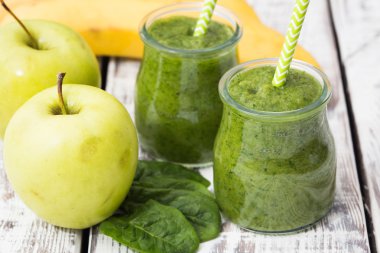 Hafif bir arka planda elma, muz ve ıspanaklı yeşil smoothie.