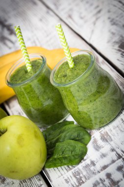 Hafif bir arka planda elma, muz ve ıspanaklı yeşil smoothie.