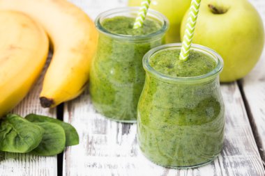 Hafif bir arka planda elma, muz ve ıspanaklı yeşil smoothie.