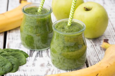 Hafif bir arka planda elma, muz ve ıspanaklı yeşil smoothie.