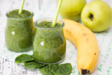Hafif bir arka planda elma, muz ve ıspanaklı yeşil smoothie.