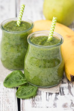 Hafif bir arka planda elma, muz ve ıspanaklı yeşil smoothie.