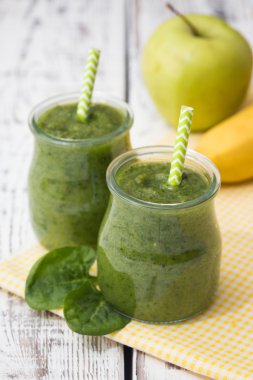 Hafif bir arka planda elma, muz ve ıspanaklı yeşil smoothie.