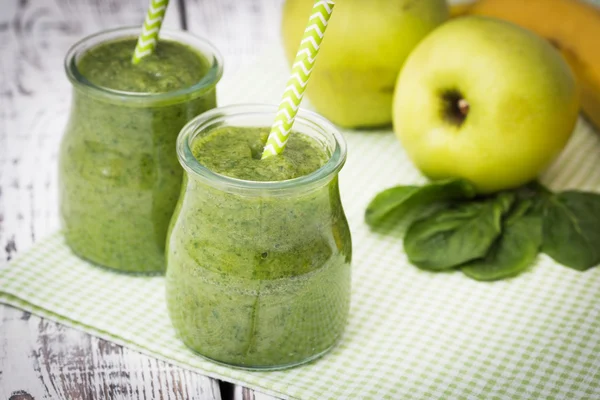 Hafif bir arka planda elma, muz ve ıspanaklı yeşil smoothie.