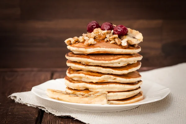 Pannkakor med körsbär, grillad banan och nötter på en mörk bakgrund — Stockfoto